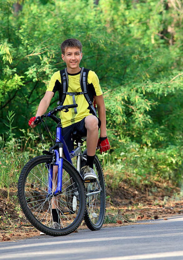 teenager riding bicycle by the woods